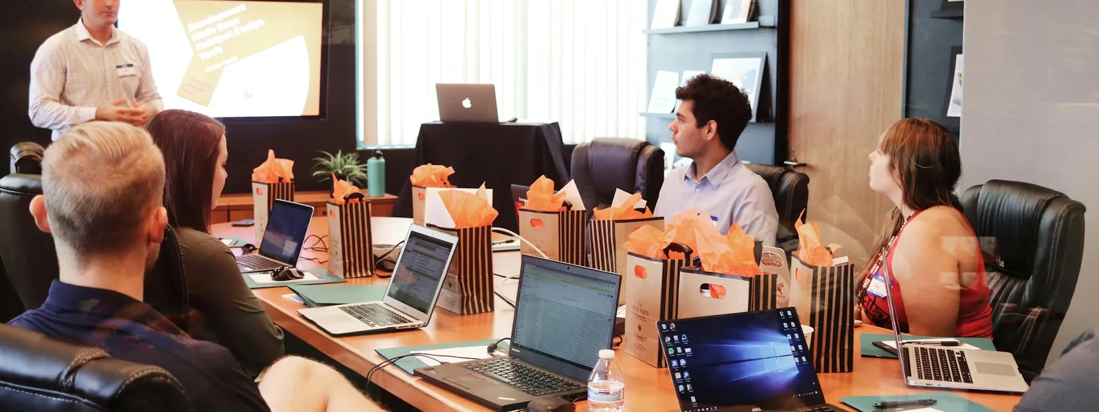 Meeting table with people watching a business presentation on a screen