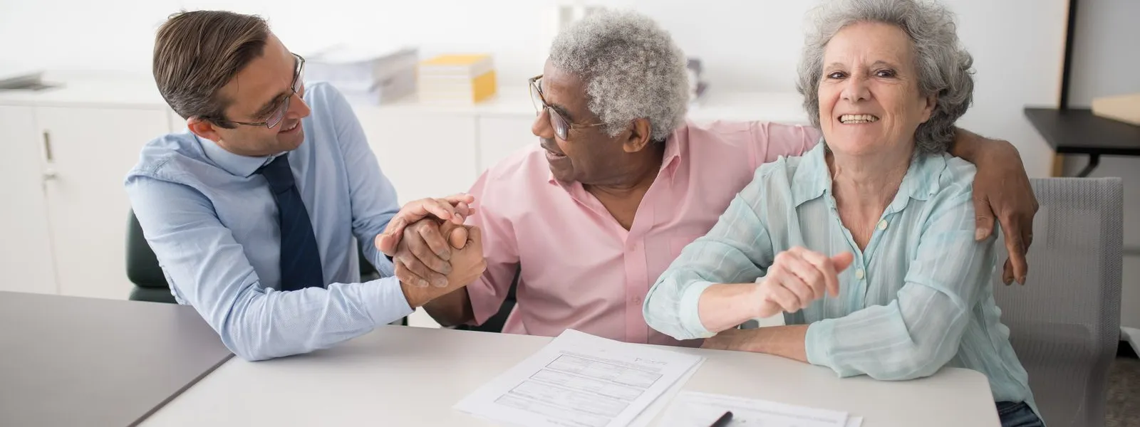 Insurance agent going over documents with two smiling clients