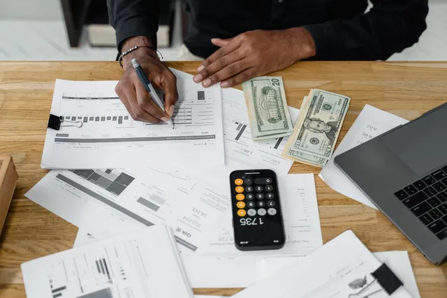 Accountant working on financial reports at a desk with a calculator and laptop