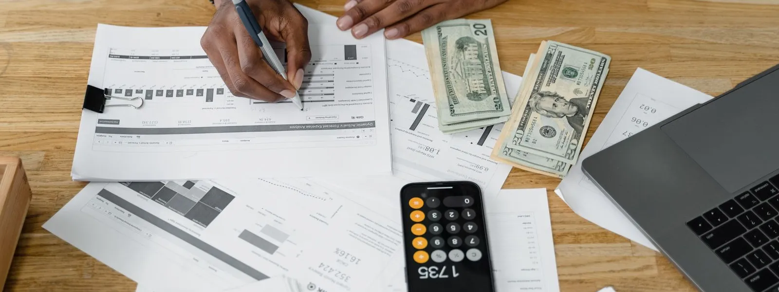 Accountant working on financial reports at a desk with a calculator and laptop